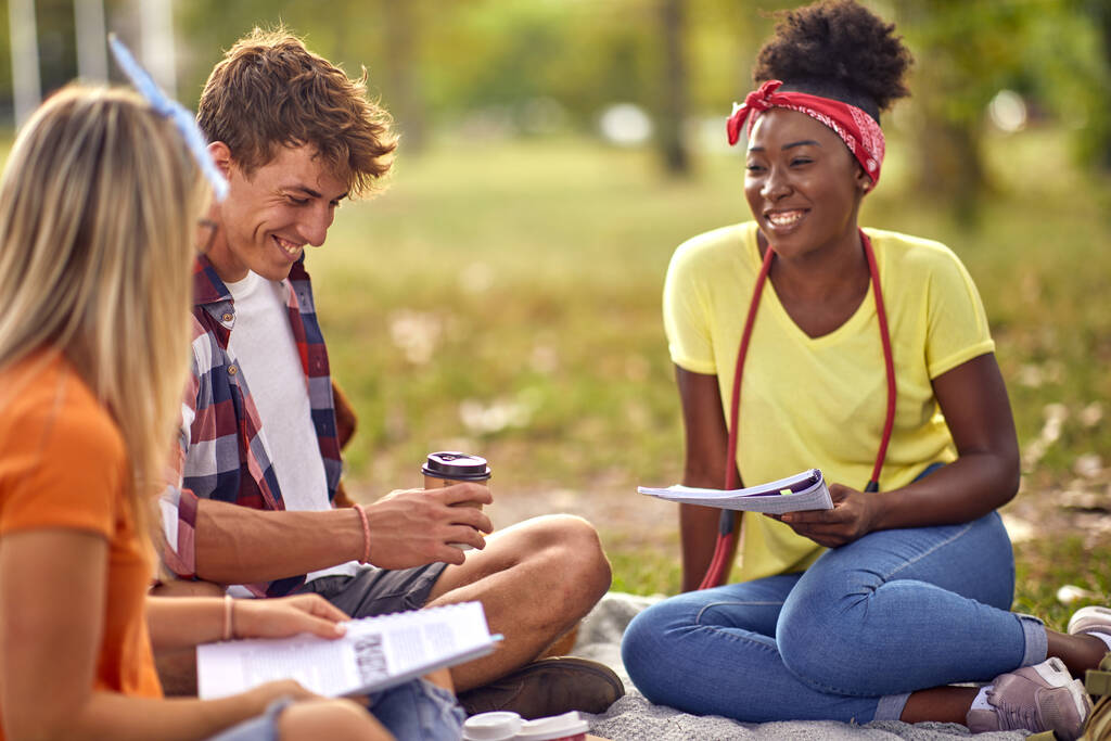 Nuori mies ottaa kahvia opiskellessaan naispuolisten ystävien kanssa collegen kampuksella
 - Valokuva, kuva
