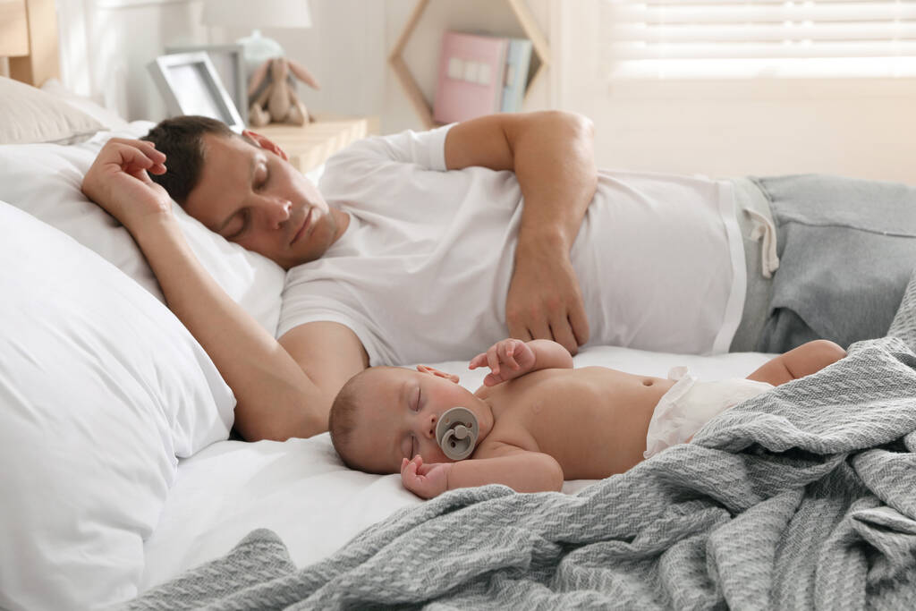 Батько зі своєю милою дитиною спить в ліжку вдома
 - Фото, зображення