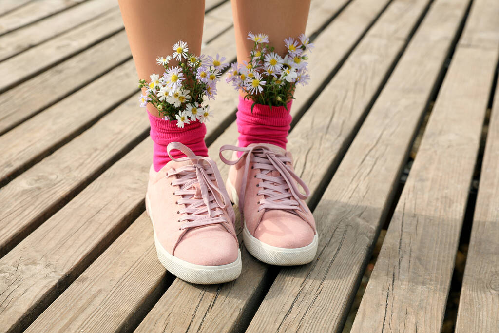 Nő gyönyörű gyengéd virágok zokniban a fa mólón, közelkép - Fotó, kép