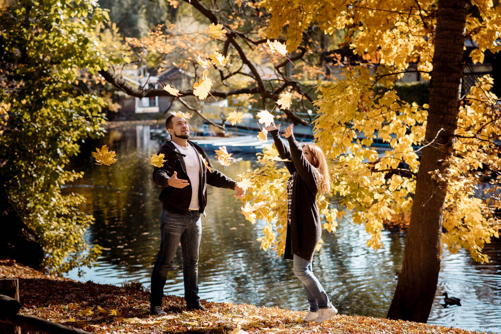 Молоді люди чоловік і жінка викидають осіннє листя восени в парку під час осіннього листя
 - Фото, зображення