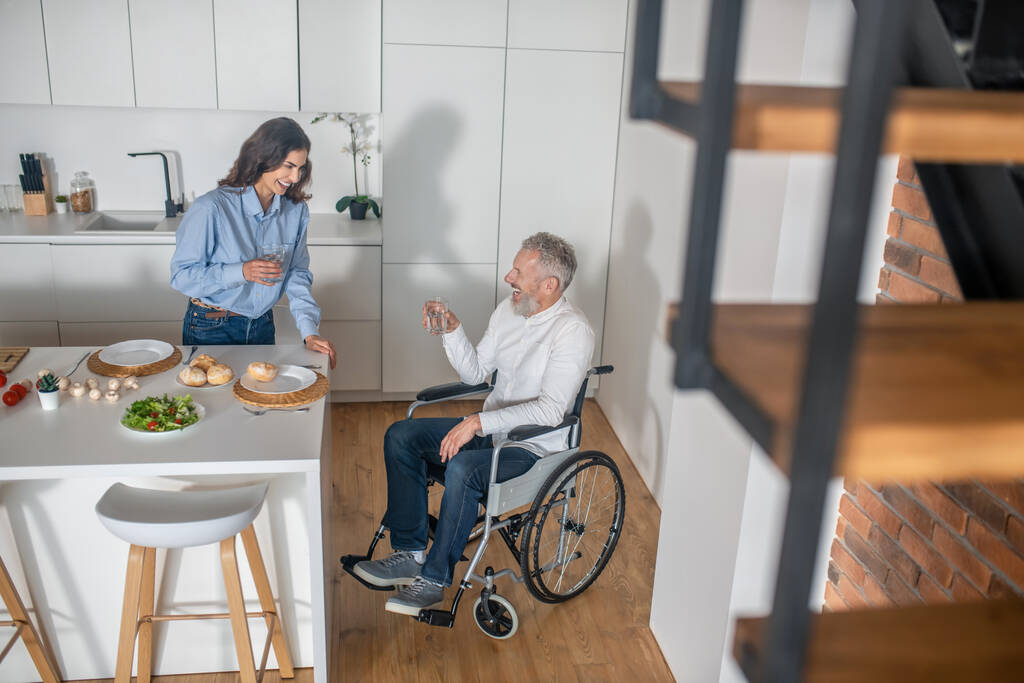 Ένας άντρας σε αναπηρική καρέκλα και η γυναίκα του περνούν το πρωινό τους μαζί. - Φωτογραφία, εικόνα