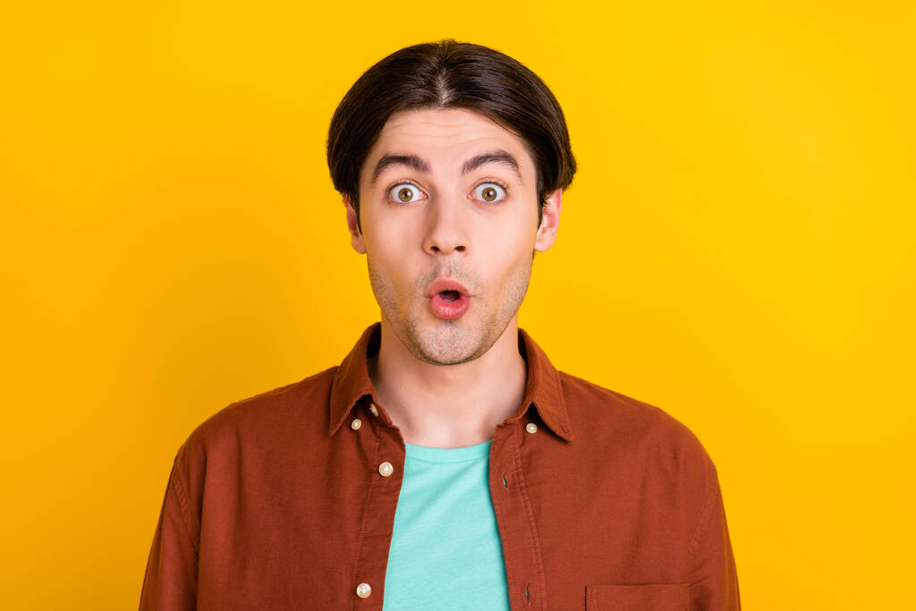 Foto von süß beeindruckt junger Mann tragen braunes Hemd große Augen isoliert gelbe Farbe Hintergrund - Foto, Bild