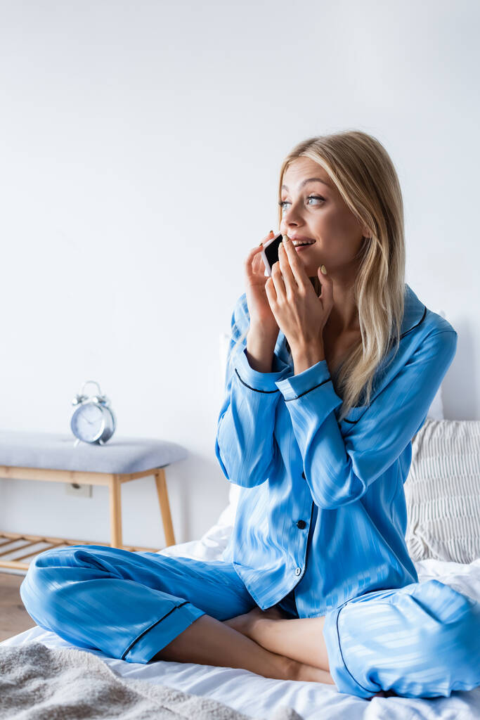 femme étonnante en pyjama parlant sur smartphone dans la chambre  - Photo, image