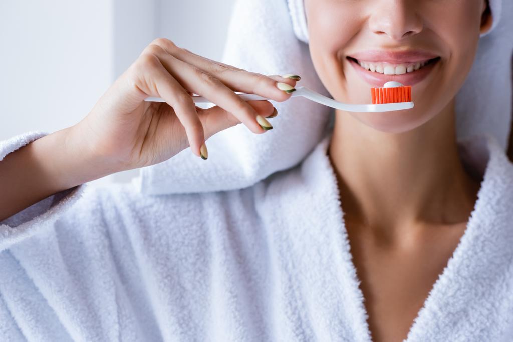 περικοπή άποψη της νεαρής χαμογελαστή γυναίκα βούρτσισμα των δοντιών στο μπάνιο  - Φωτογραφία, εικόνα