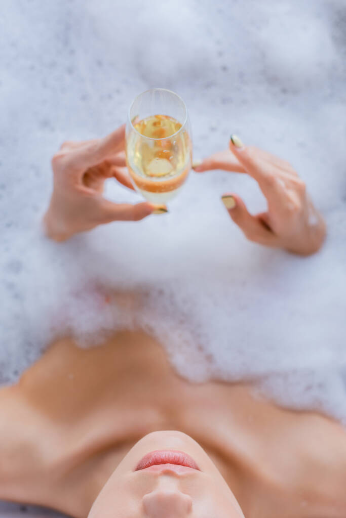 kivágott kilátás nő fürdés és kezében pohár pezsgő  - Fotó, kép
