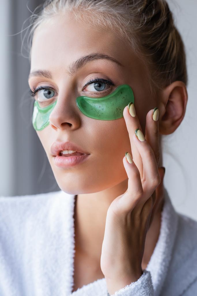 молода жінка в халаті застосовує зелені плями для очей у ванній
  - Фото, зображення