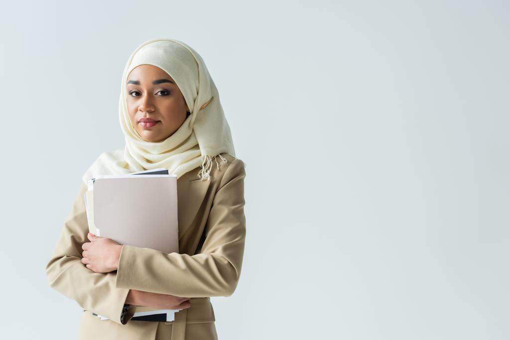 tyylikäs muslimi liikenainen hijabissa ja beige puku tilalla kansiot eristetty harmaa  - Valokuva, kuva