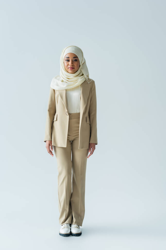 plná délka muslimské ženy v hidžábu a béžový oblek stojící na šedé  - Fotografie, Obrázek