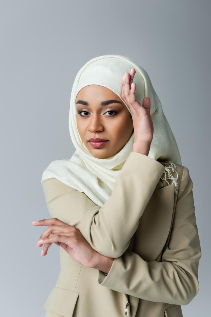 Portret van moslim vrouw in hijab kijken naar camera terwijl poseren geïsoleerd op grijs - Foto, afbeelding