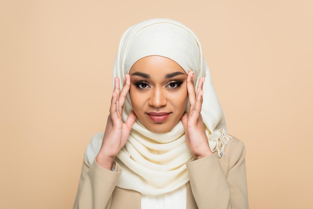 Portrét usměvavé muslimky v hidžábu s make-upem izolovaným na béžové  - Fotografie, Obrázek