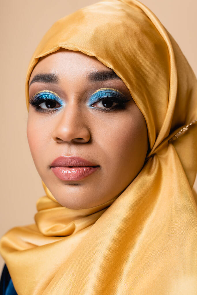 黄色のヒジャーブの可愛いイスラム教徒の女性ベージュで孤立した明るいメイクで - 写真・画像