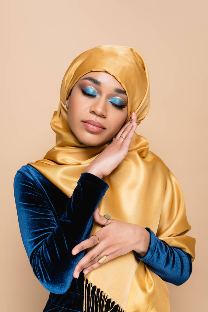 young muslim woman in yellow hijab posing with closed eyes isolated on beige - Photo, Image