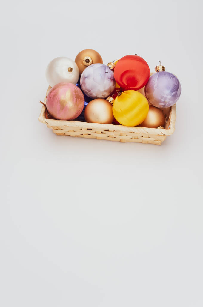 Bolas decorativas navideñas multicolores en un bote de mimbre con sapce para texto - Foto, Imagen