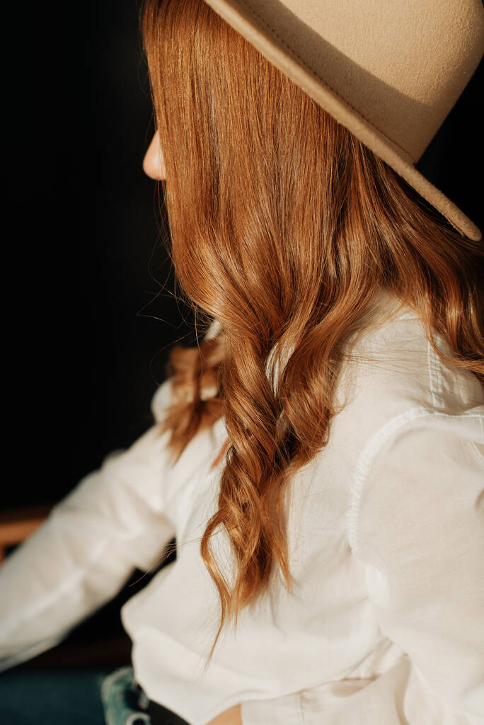 νεαρή κοπέλα με κόκκινα μαλλιά και μεγάλο καπέλο από κοντά. - Φωτογραφία, εικόνα