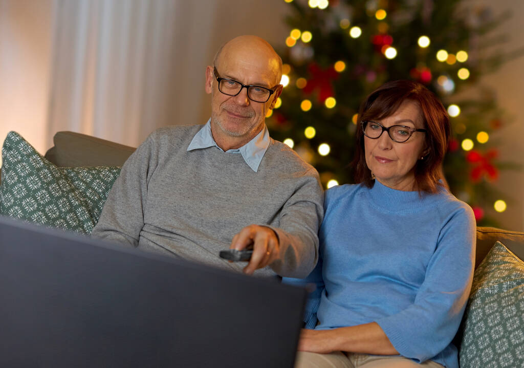 пожилая пара смотрит телевизор дома на Рождество - Фото, изображение