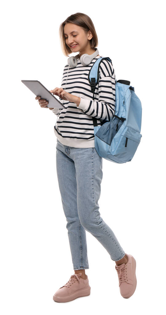 Joven estudiante con tablet, mochila y auriculares sobre fondo blanco - Foto, imagen