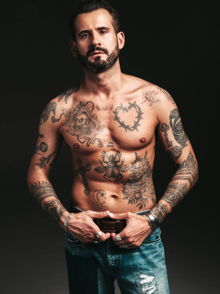 Portrait of handsome confident stylish hipster lambersexual model. Sexy modern man. Naked torso with tattoos.Fashion male posing in studio on dark background - Photo, Image