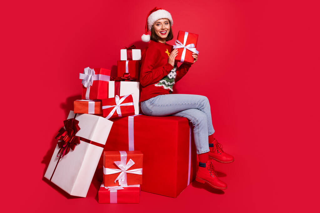 Fénykép funky édes fiatal hölgy öltözött nyomtatott pulóver előkészítése Noel ajándékok elszigetelt piros szín háttér - Fotó, kép