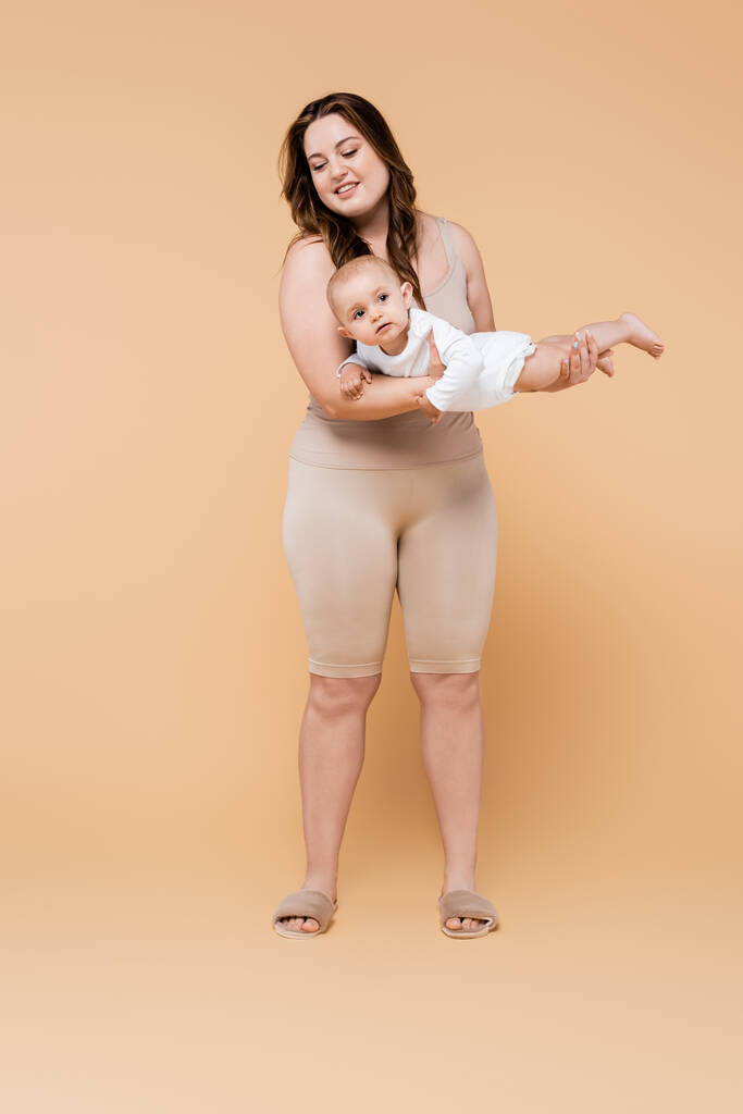 Happy plus taille mère tenant bébé fille sur fond beige  - Photo, image