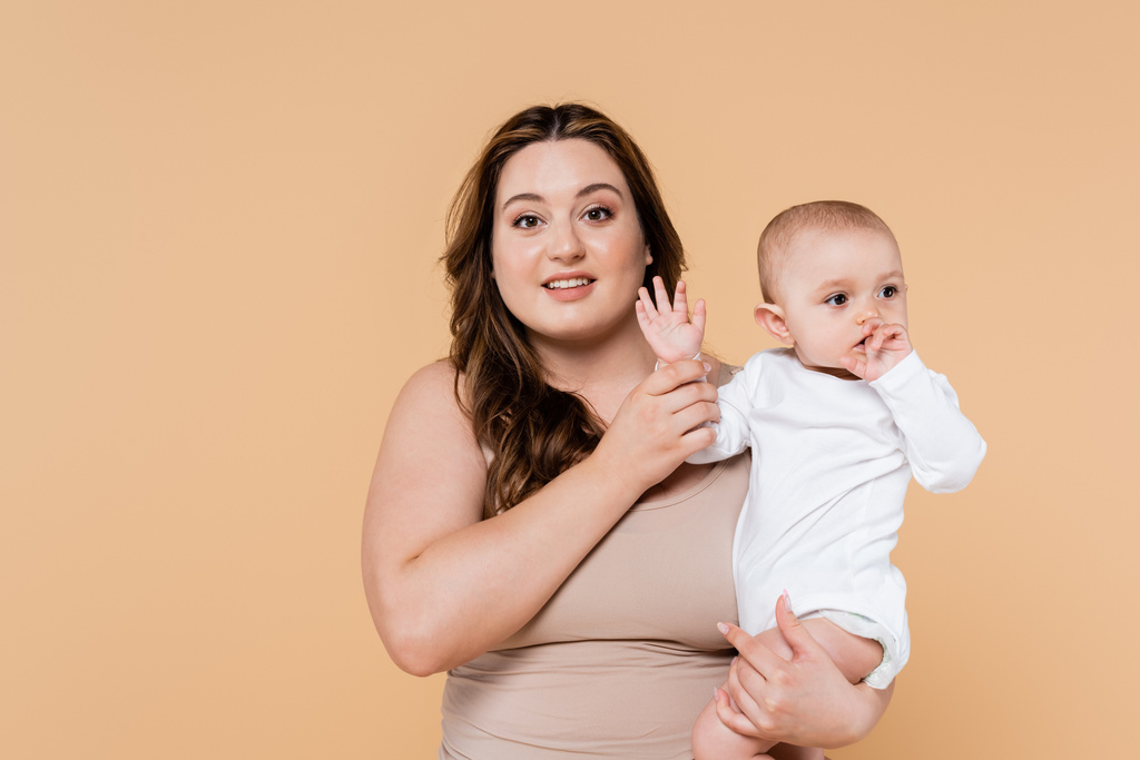 Hymyilevä plus koko vanhempi tilalla käsi vauva tytär eristetty beige  - Valokuva, kuva