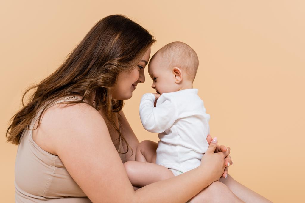 Side view of woman with overweight holding baby daughter isolated on beige  - Photo, Image
