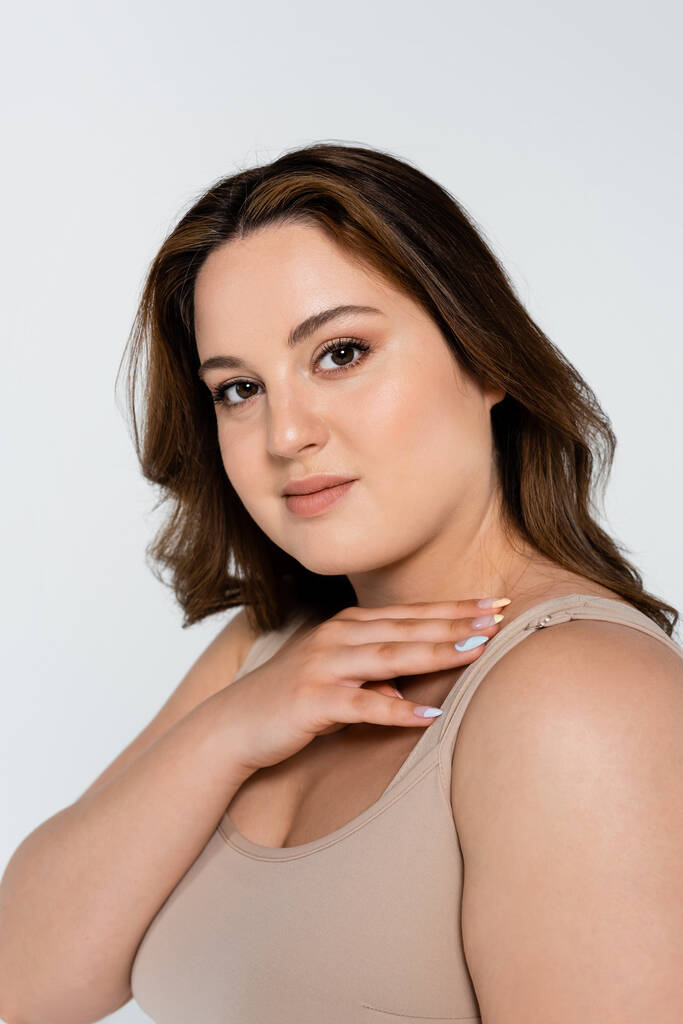 Portrait of young brunette plus size woman looking at camera isolated on grey - Photo, Image