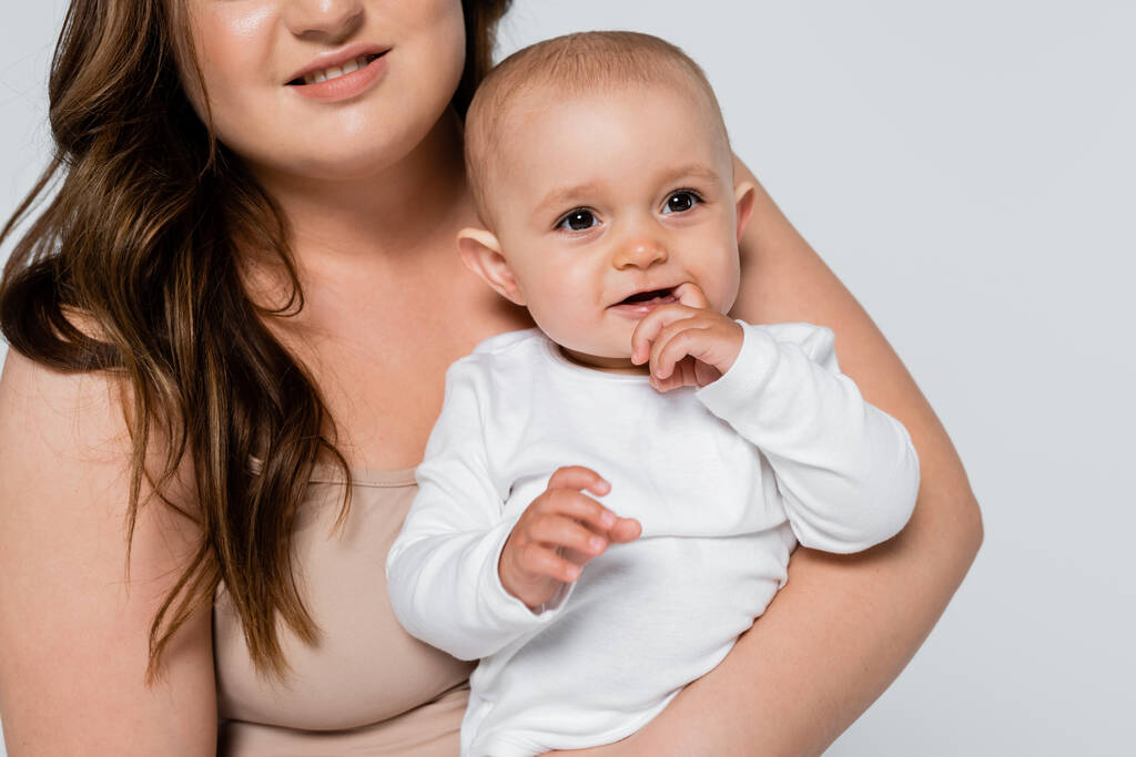 Plus size mother holding positive baby girl isolated on grey - Photo, Image