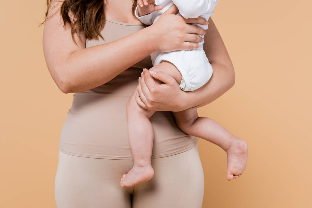 Ausgeschnittene Ansicht des Körpers positive Frau umarmt Kind isoliert auf beige  - Foto, Bild