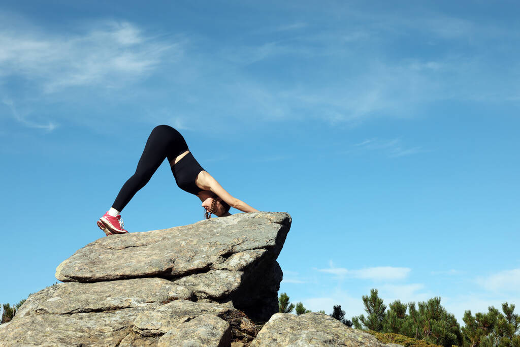 Krásná mladá žena cvičit jógu na skále v horách - Fotografie, Obrázek