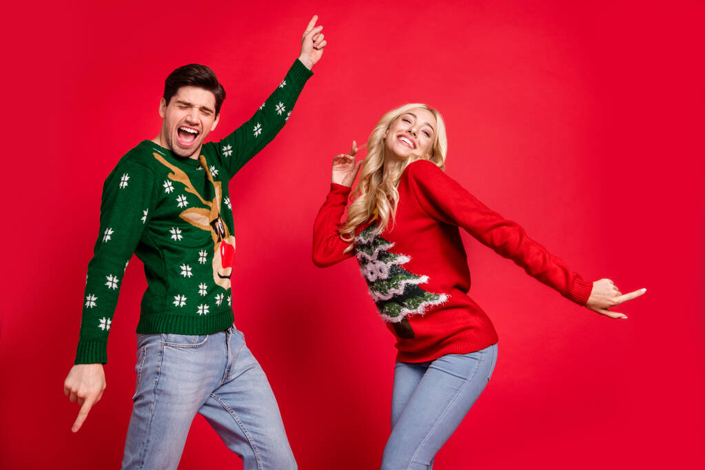 Фотопортрет сміється пара в светрах танцює на Різдвяній вечірці, святкуючи свята ізольований яскраво-червоний колір фону
 - Фото, зображення