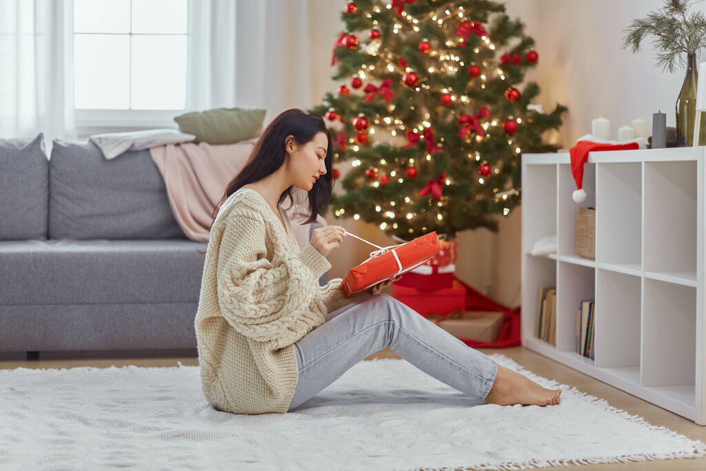 Nő jelennel az ajándékdobozban Közel karácsonyfa otthon - Fotó, kép