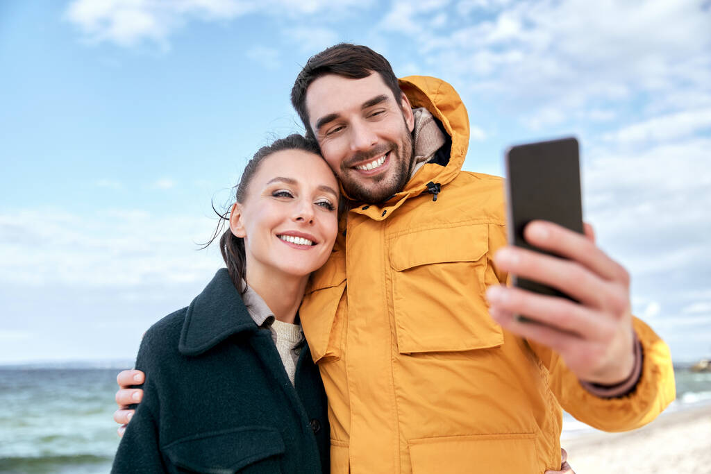 Paar mit Smartphone am Herbststrand - Foto, Bild