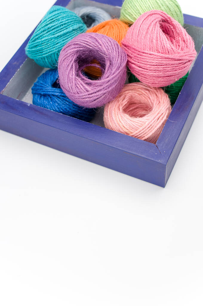 boules de fils décoratifs multicolores dans une boîte en bois sur une surface blanche - Photo, image