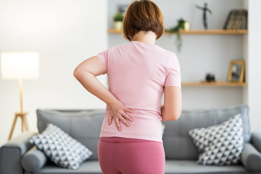 Dor nas costas, inflamação dos rins, mulher que sofre de dor nas costas em casa, conceito de problemas de saúde - Foto, Imagem