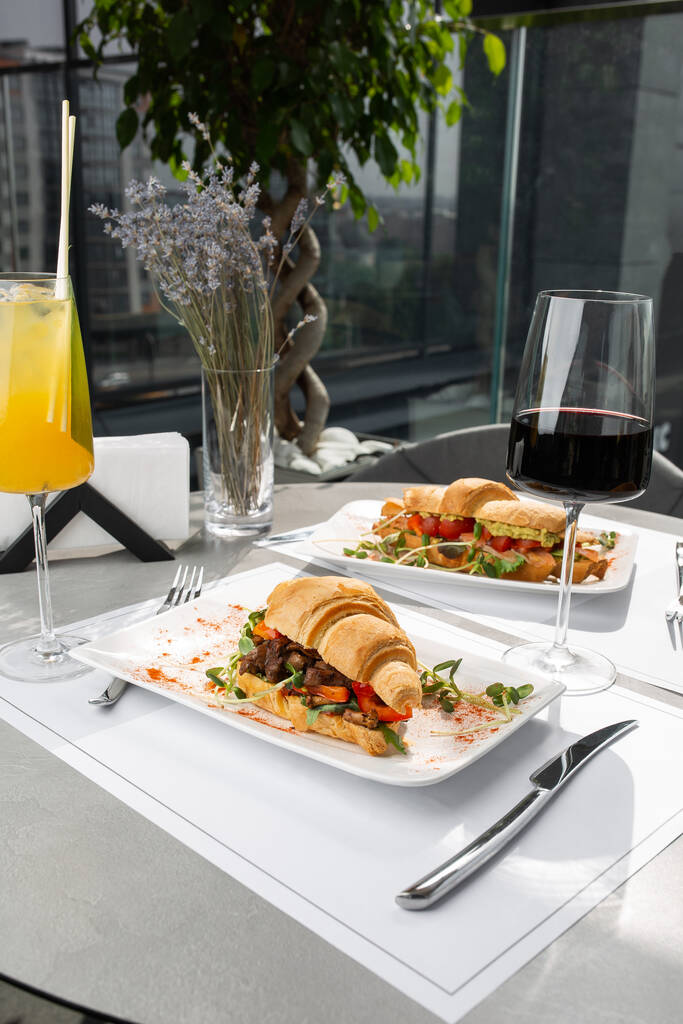 Dva druhy croissant sendviče s masem, rajčaty a salátem a avokádem na jasném pozadí. Kontinentální styl snídaně. - Fotografie, Obrázek