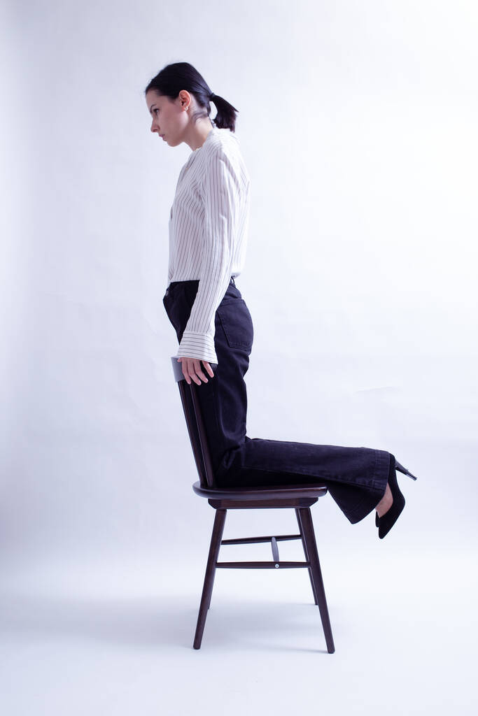 mujer en camisa blanca y pantalones negros se sienta en una silla - Foto, Imagen
