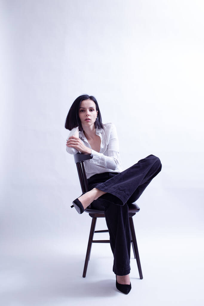 donna in camicia bianca e pantaloni neri seduta su una sedia - Foto, immagini