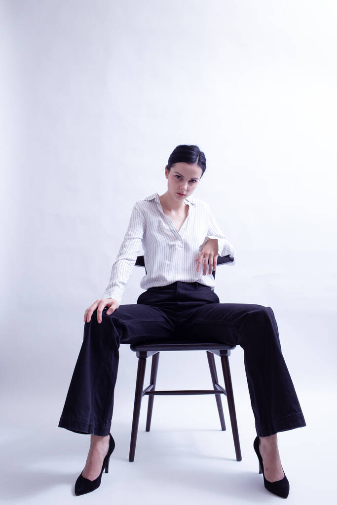 kobieta w białej koszuli i czarne spodnie siedzi na krześle - Zdjęcie, obraz
