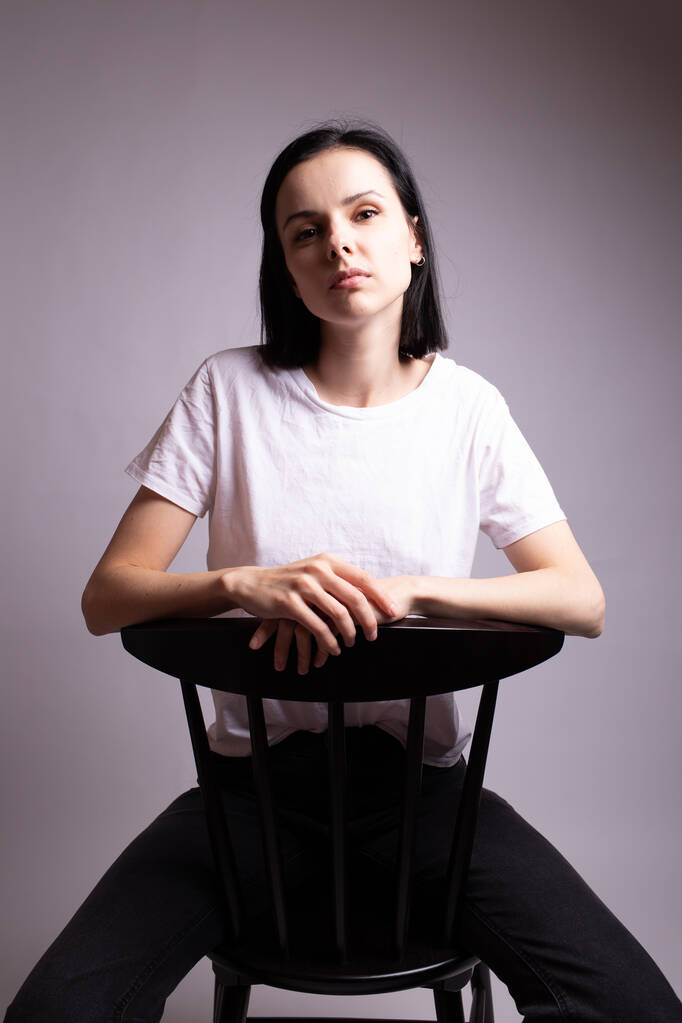 fille dans un t-shirt blanc assis sur une chaise dans le studio - Photo, image