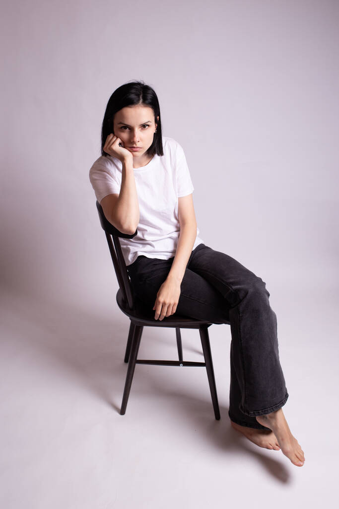 Mädchen im weißen T-Shirt sitzt auf einem Stuhl im Studio - Foto, Bild