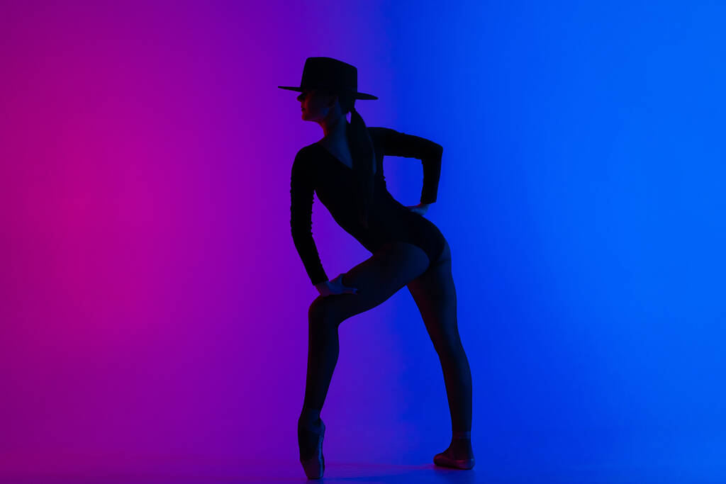 Şapkalı çağdaş balerin kadın çok renkli gradyan pembe arka planda poz veriyor. Femme fatale kostümlü profesyonel balerin, solo performans. - Fotoğraf, Görsel