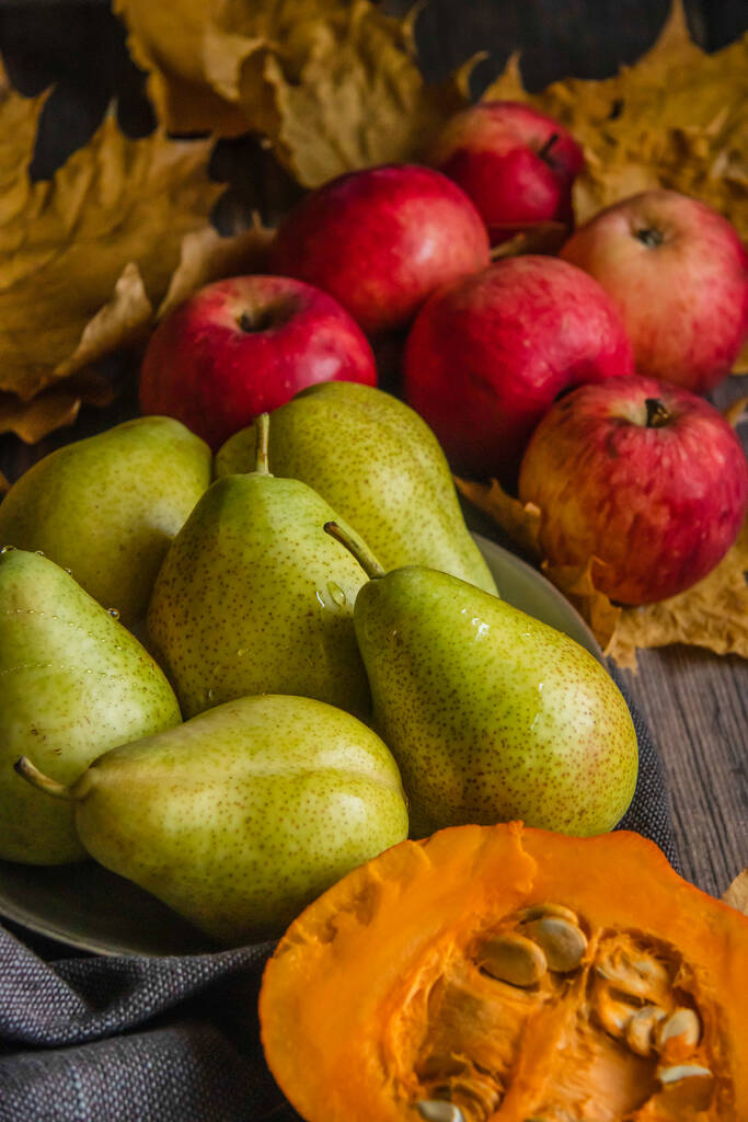осіннє натюрморт з груш, яблук, гарбуза і жовтого листя на дерев'яному столі
 - Фото, зображення