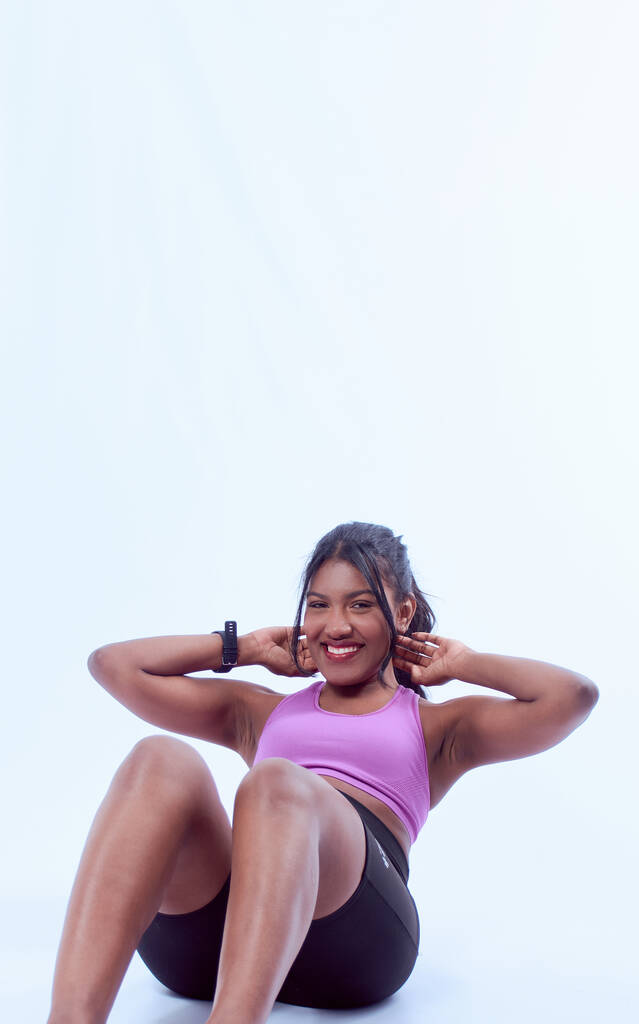 Una joven mujer en un equipo deportivo haciendo un entrenamiento de abdominales - Foto, Imagen