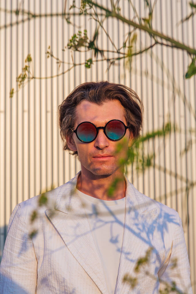Retrato de cerca de un hombre guapo con gafas de sol hippie redondas durante el atardecer - Foto, Imagen