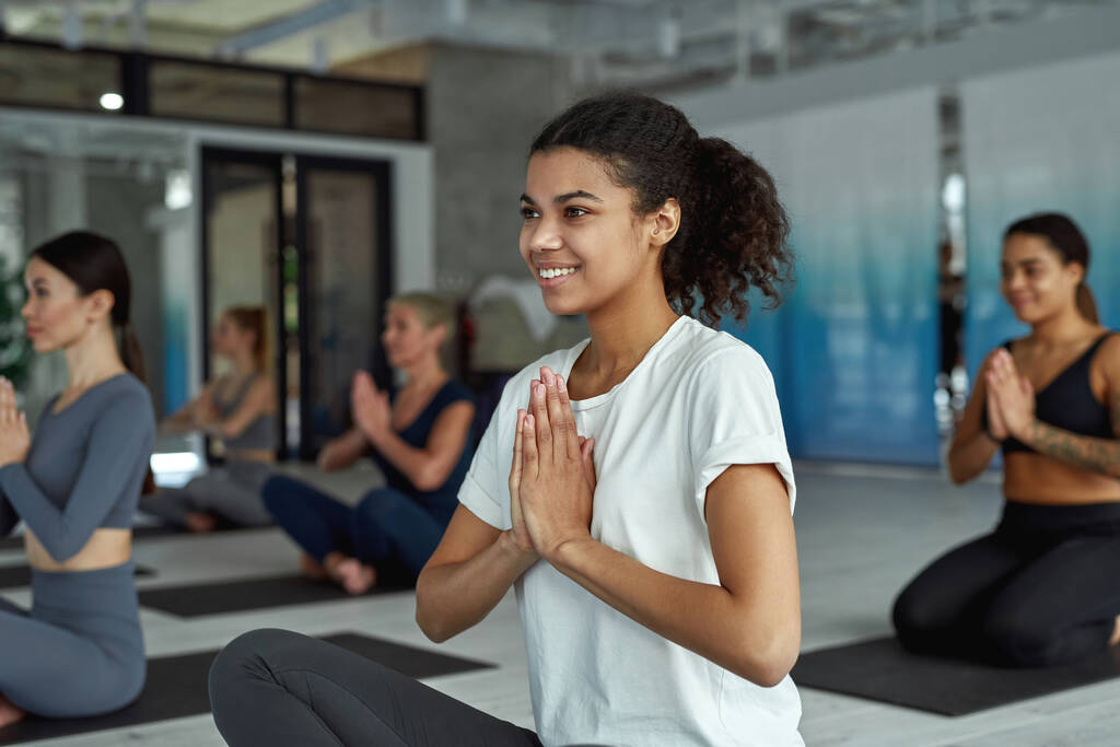 Menina sorridente ativa meditar prática de ioga no treinamento em grupo - Foto, Imagem