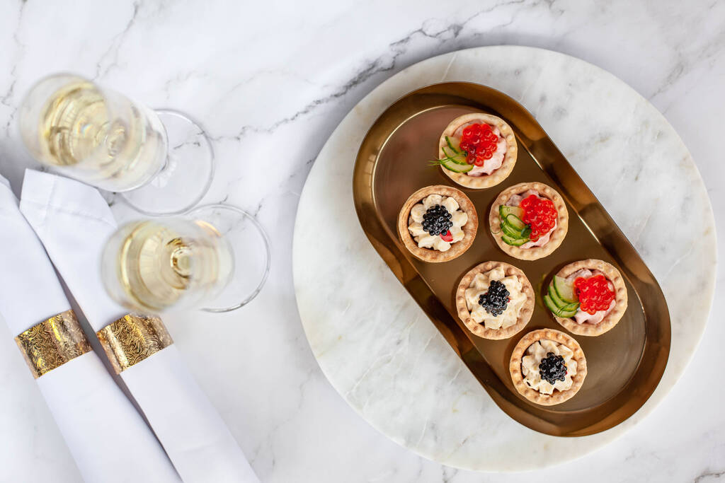 Canape mit schwarzem Kaviar und saurer Sahne neben Glas mit Champagner - Foto, Bild
