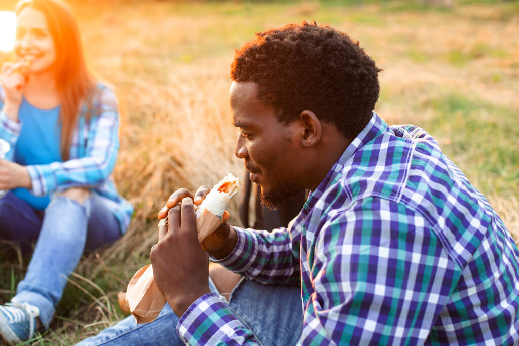 A boldog középiskolás diák kint ül és kebabot eszik. - Fotó, kép