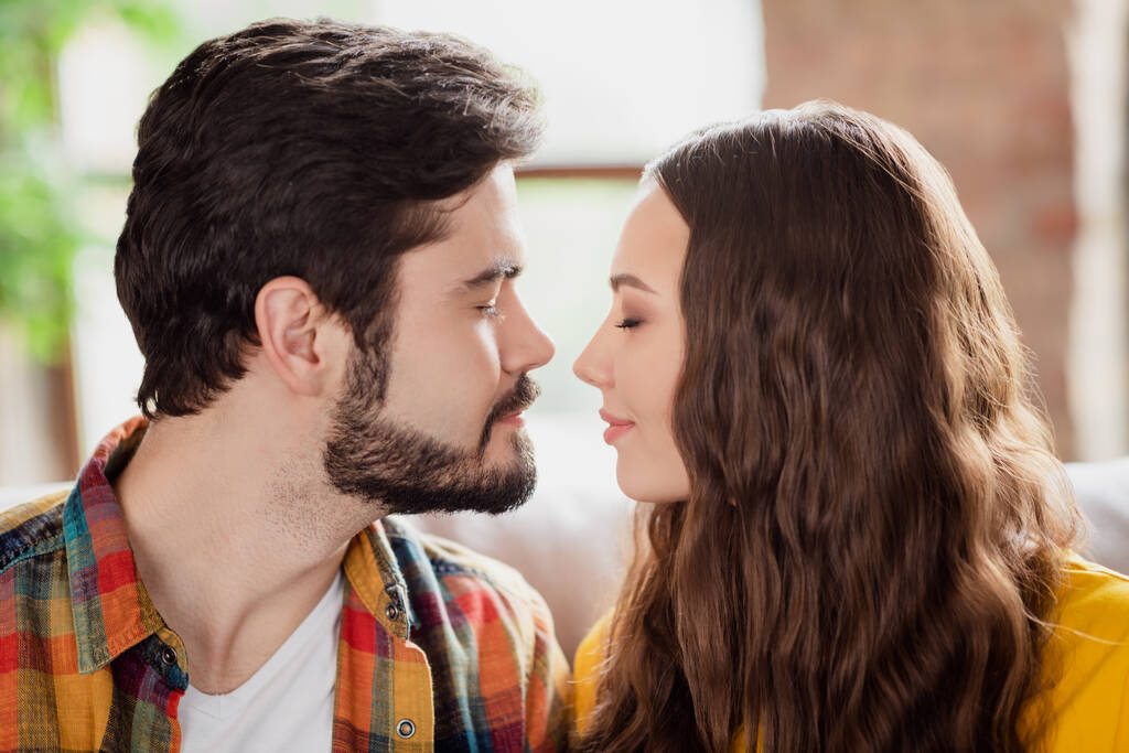 Zdjęcie romantyczne słodkie młoda para nosić casual stroje siedzi kanapa zamknięte oczy gotowy całowanie wewnątrz domu pokój - Zdjęcie, obraz