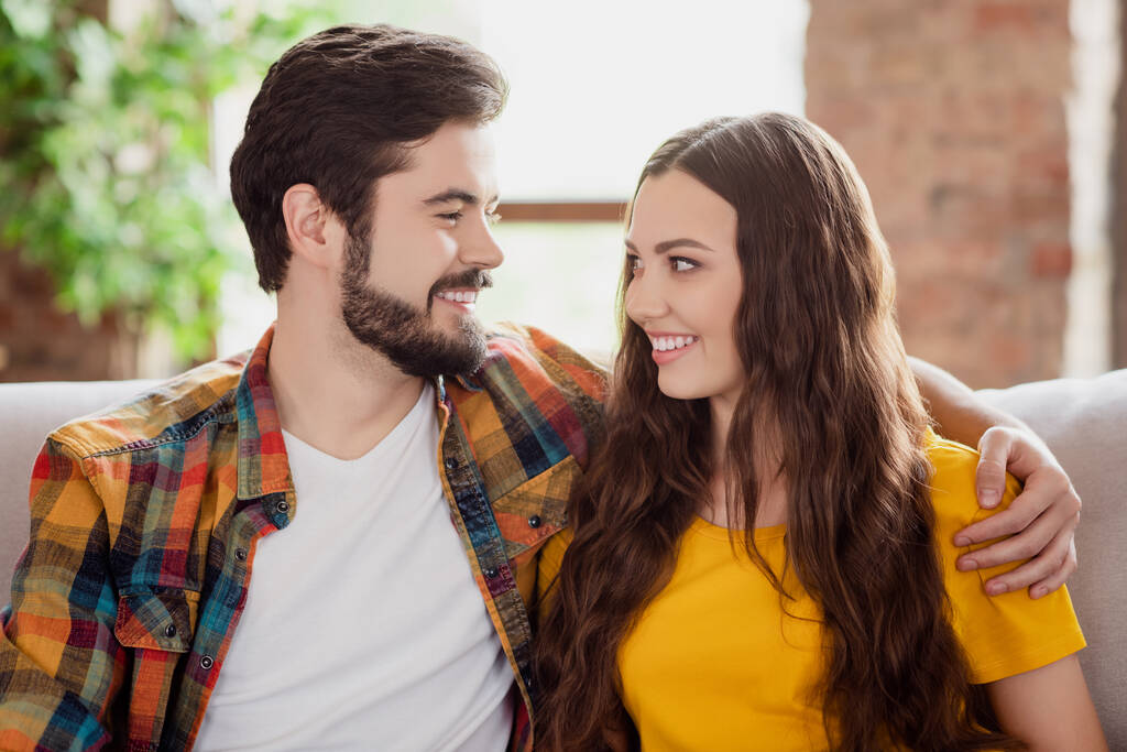 Фото веселих ніжних пар охоплює один одного зубна посмішка носіння повсякденного одягу сидить диван додому в приміщенні
 - Фото, зображення