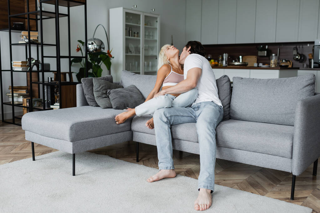 homem beijando pescoço de loira namorada com olhos fechados na sala de estar - Foto, Imagem